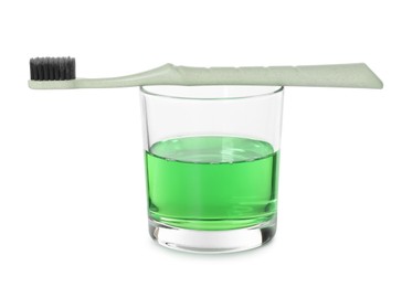 Photo of Glass of mouthwash and toothbrush isolated on white