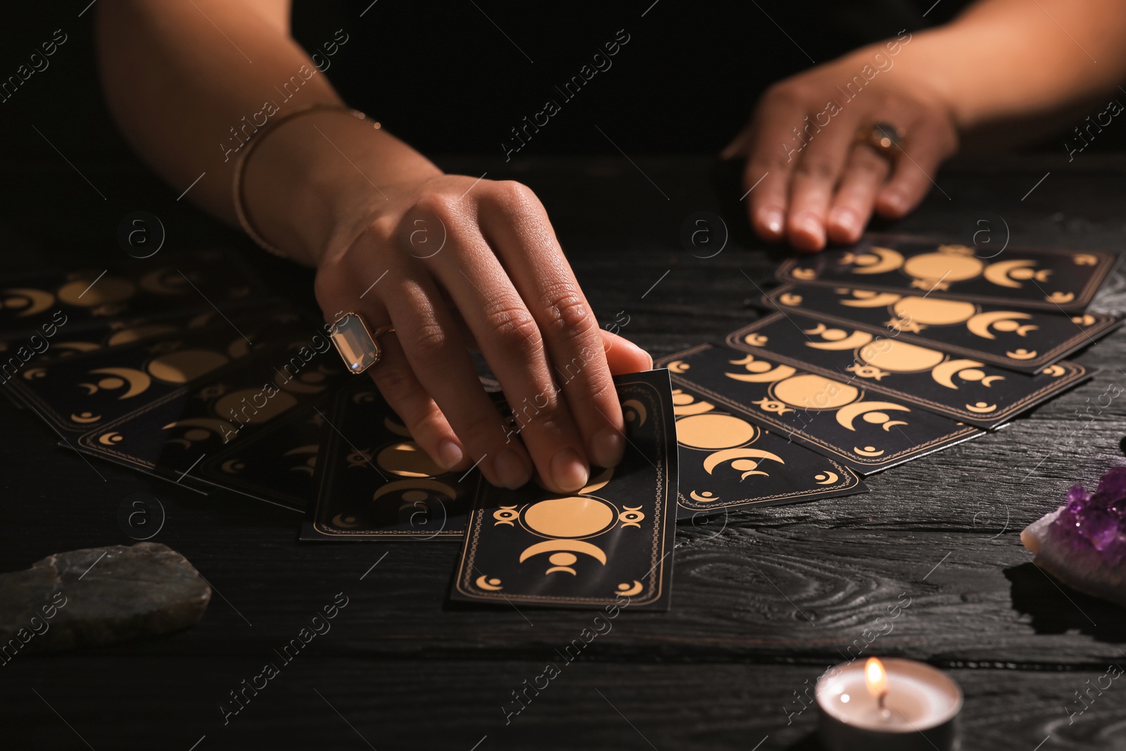 Photo of Soothsayer predicting future with tarot cards at table in darkness, closeup