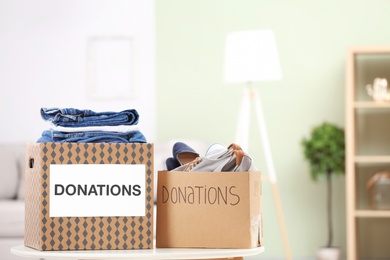 Photo of Donation boxes with clothes and shoes on table indoors