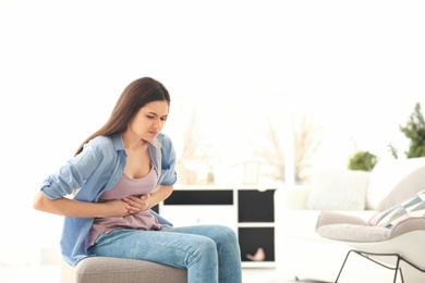 Photo of Young woman suffering from stomach ache at home