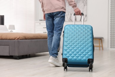 Photo of Guest with suitcase walking in hotel room, closeup