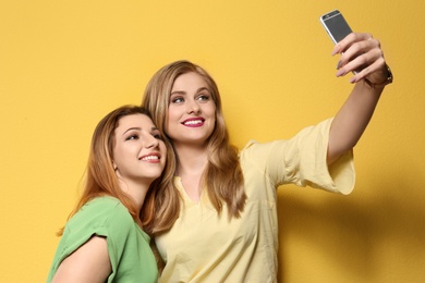 Photo of Attractive young women taking selfie on color background