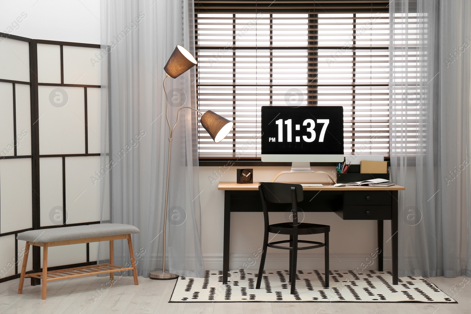 Photo of Comfortable workplace near window with blinds in room