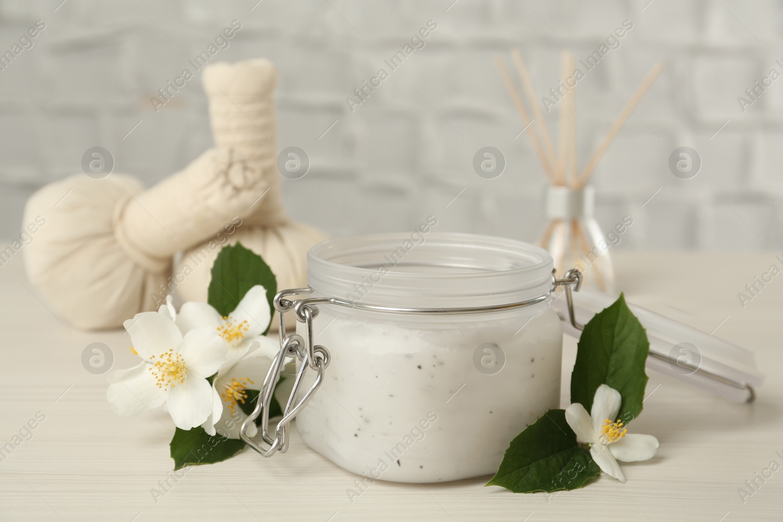 Photo of Jar of salt scrub and beautiful jasmine flowers on white wooden table