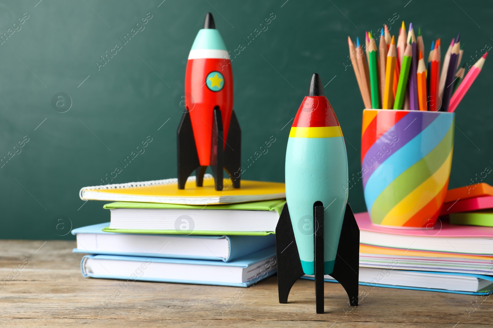 Photo of Bright toy rockets and school supplies on wooden table