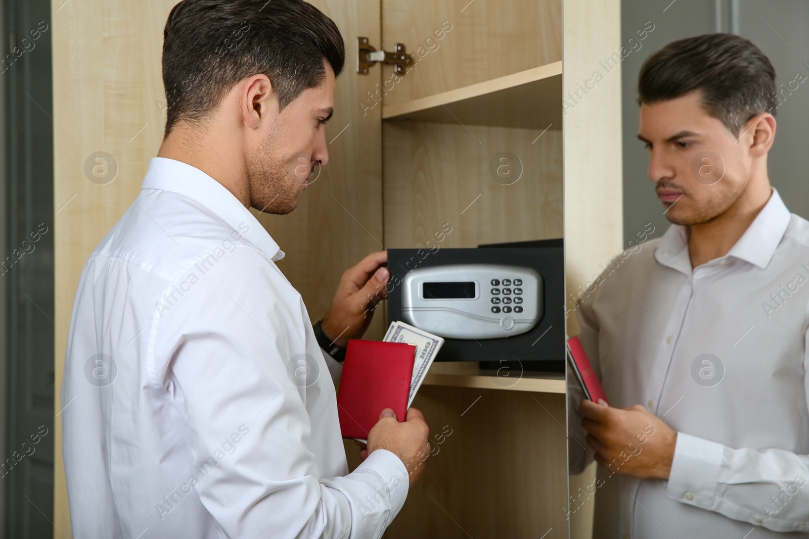 Photo of Man opening black steel safe with electronic lock at hotel