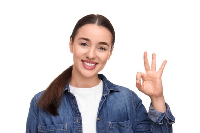 Young woman with clean teeth smiling and showing ok gesture on white background