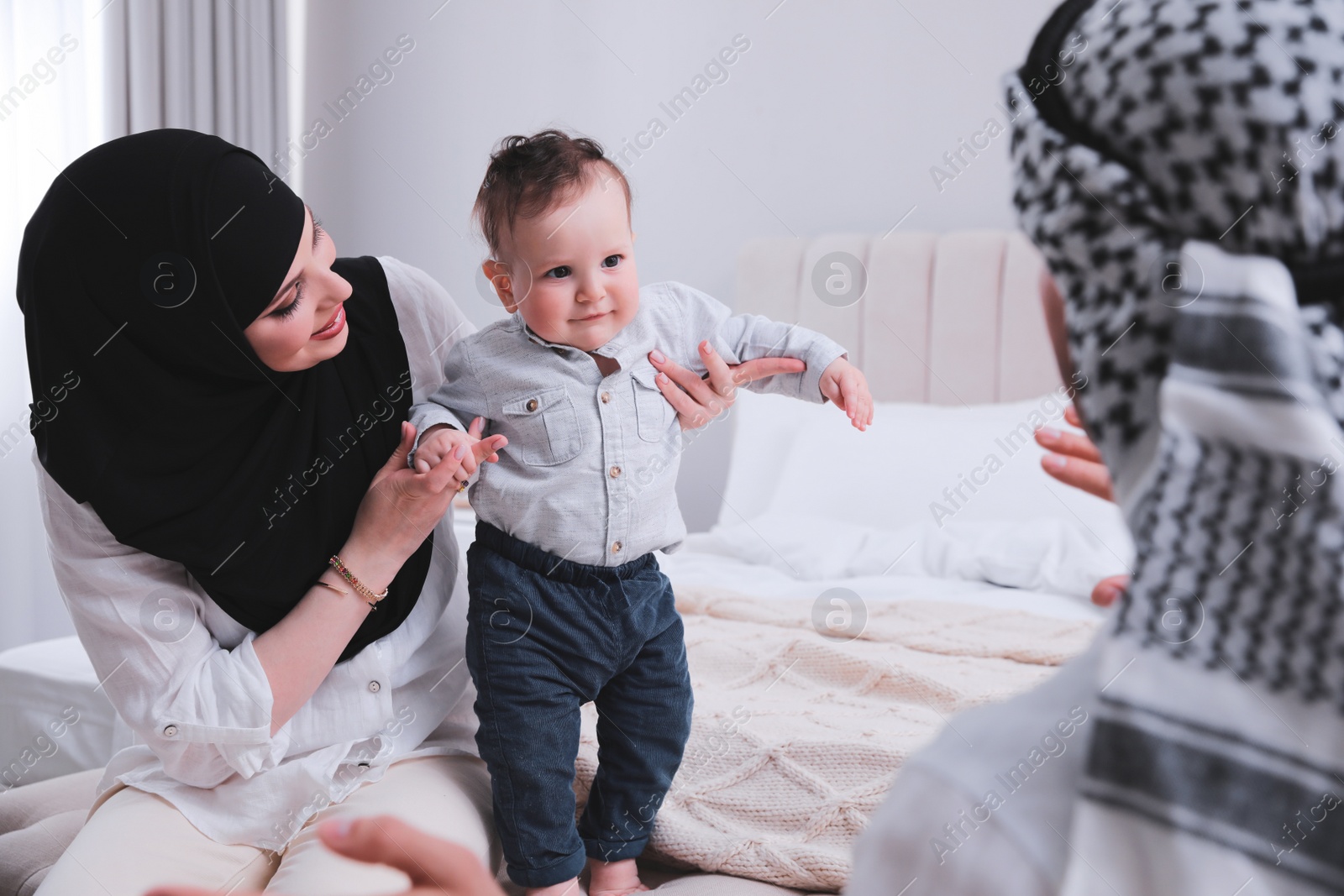 Photo of Happy Muslim family with little son in bedroom