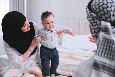 Happy Muslim family with little son in bedroom