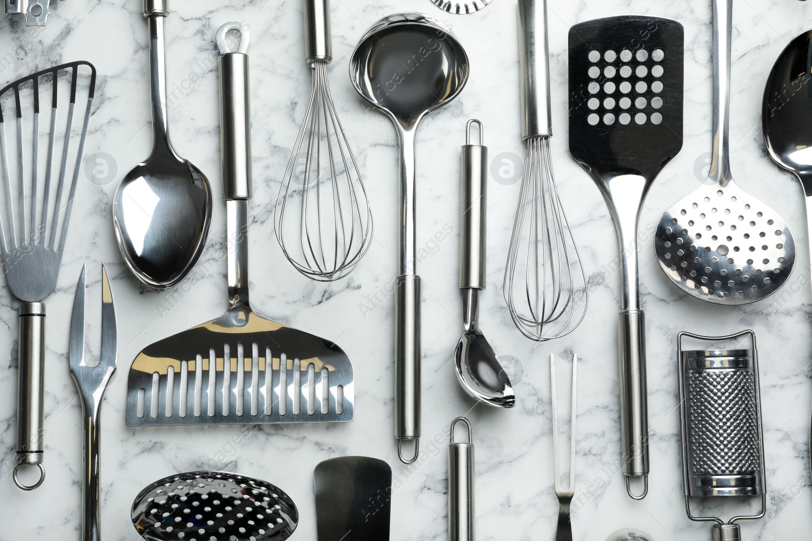 Photo of Different kitchen utensils on marble background, flat lay