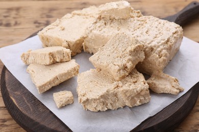 Photo of Pieces of tasty halva on wooden table, closeup