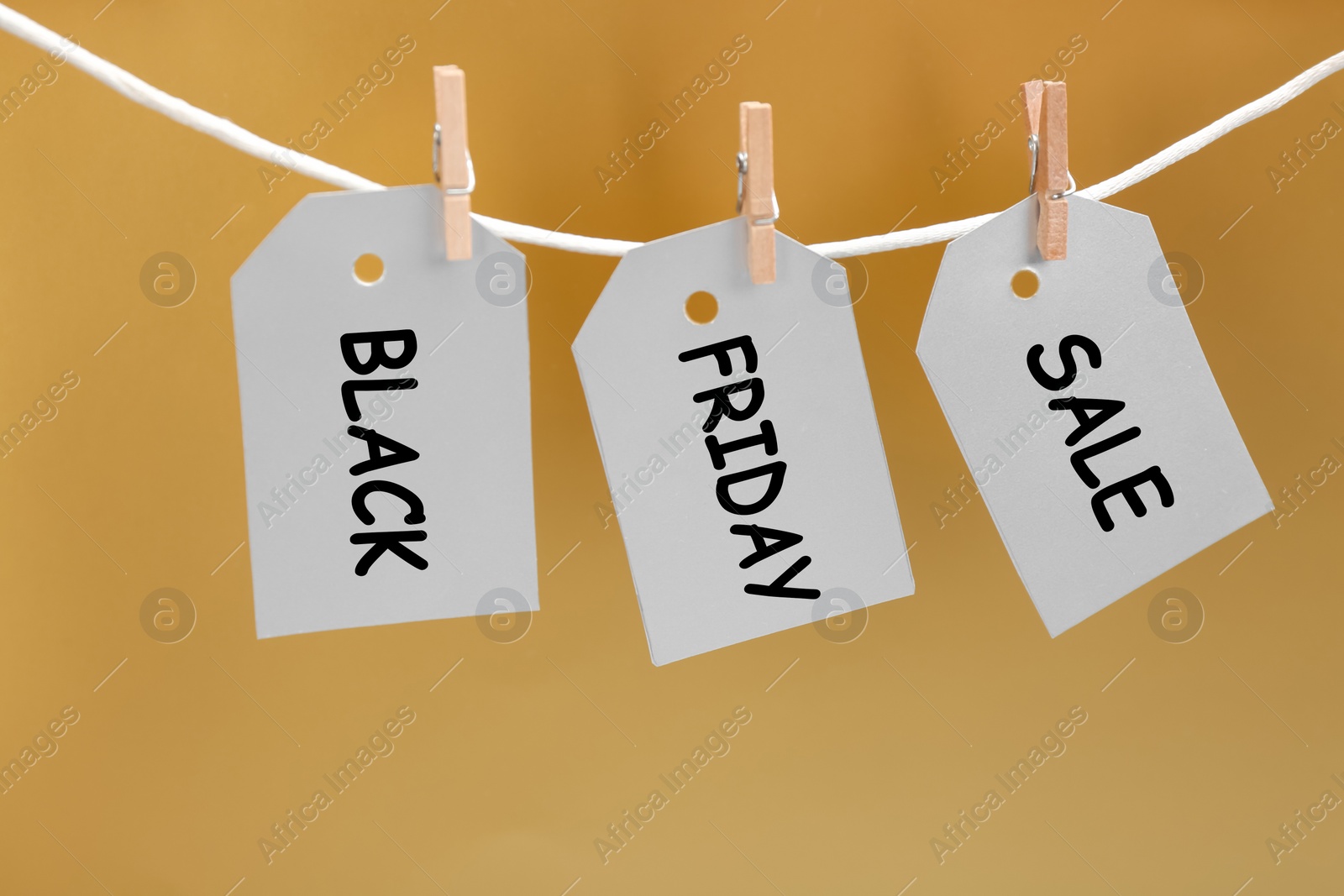 Photo of Blank tags hanging on golden background. Black Friday concept