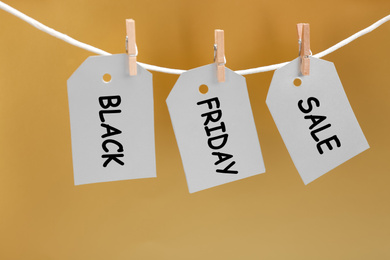 Photo of Blank tags hanging on golden background. Black Friday concept
