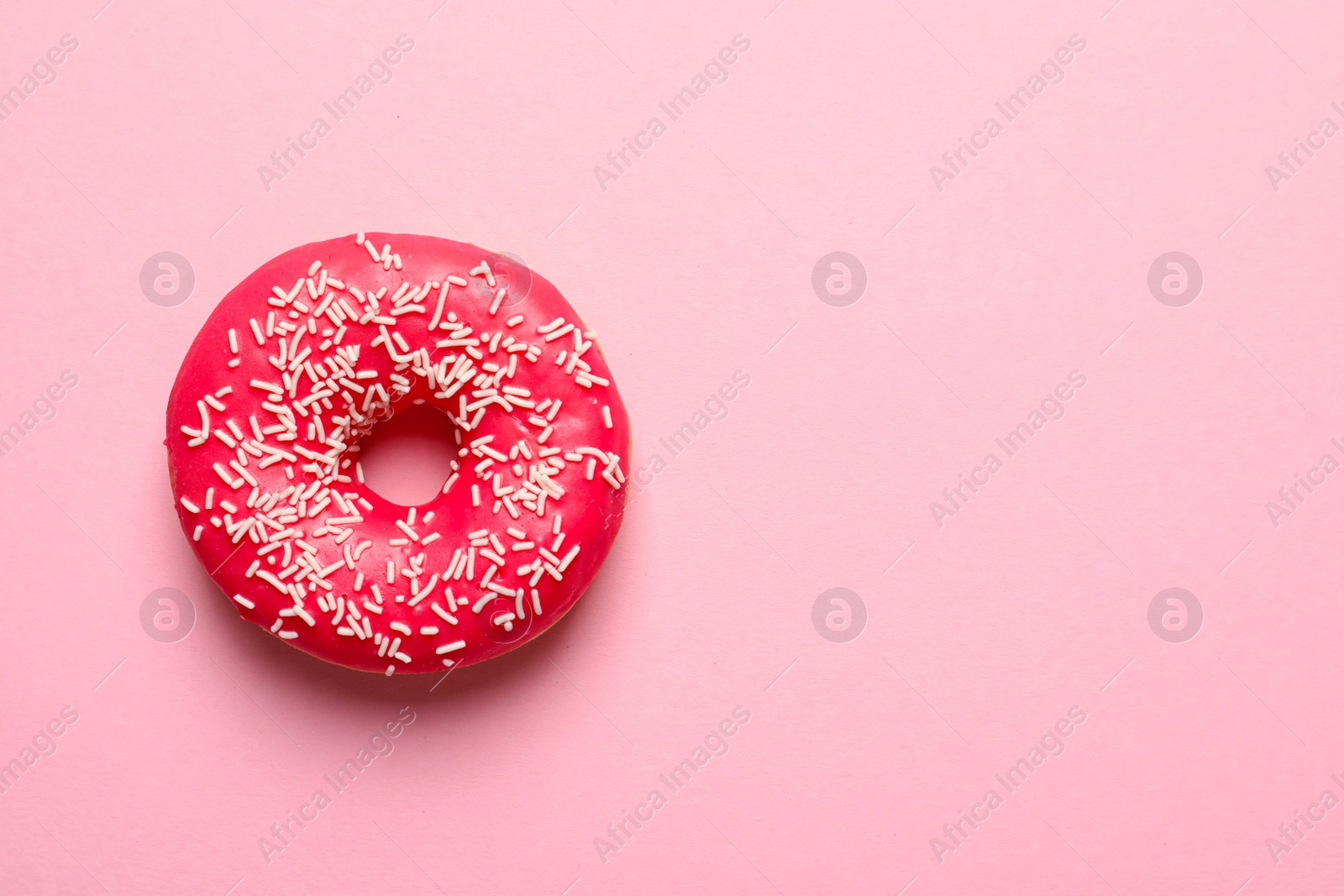 Photo of Delicious glazed doughnut with sprinkles on color background, top view