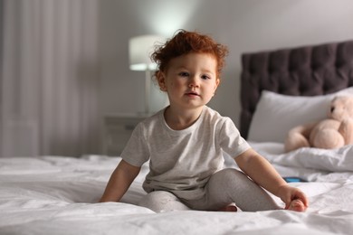 Cute little child sitting on bed at home