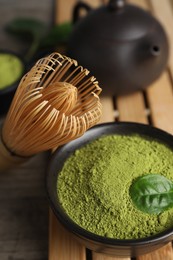 Photo of Green matcha powder and bamboo whisk on table, closeup