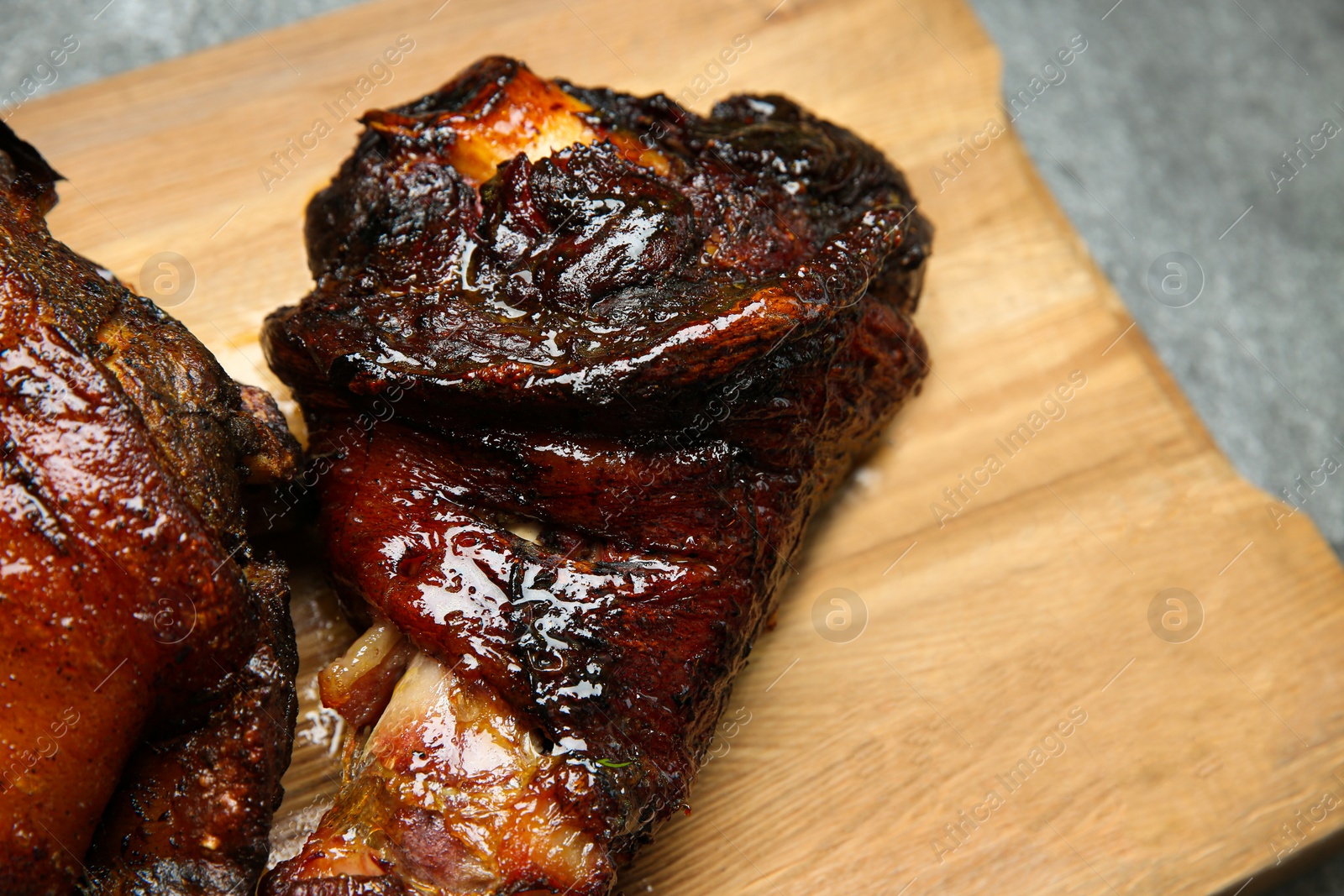 Photo of Delicious roasted pork foreshanks on wooden board, closeup