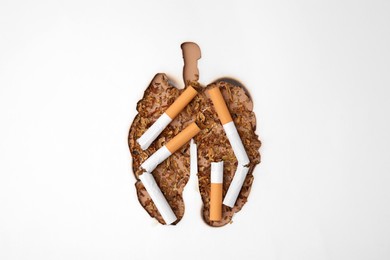 Photo of No smoking concept. Top view of dry tobacco and cigarettes through burned lungs shaped paper