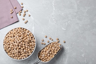 Photo of Bowl and scoop with chickpeas on light grey table, flat lay. Space for text