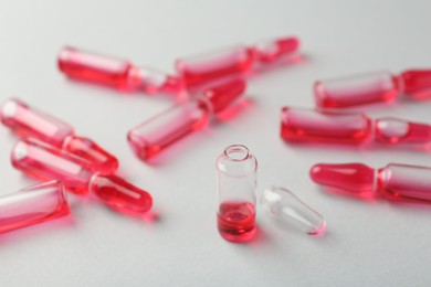 Photo of Glass ampoules with liquid on white background, closeup