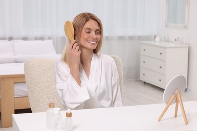 Beautiful woman brushing her hair at vanity in bedroom