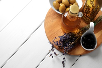 Photo of Different cooking oils and ingredients on white wooden table, space for text