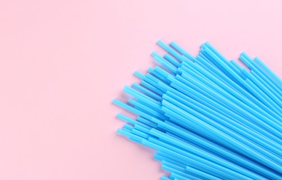 Photo of Heap of blue plastic drinking straws on pink background, flat lay. Space for text