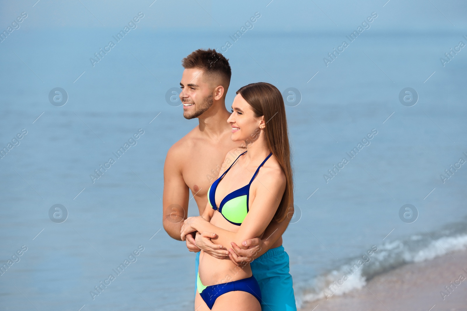 Photo of Young woman in bikini with her boyfriend on beach. Lovely couple