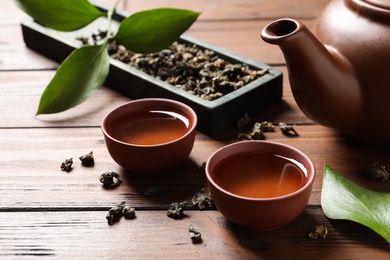 Photo of Cups and teapot of Tie Guan Yin oolong on wooden table