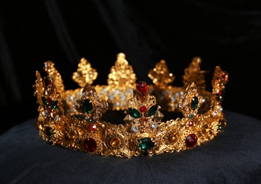 Photo of Beautiful golden crown on black velvet pillow. Fantasy item