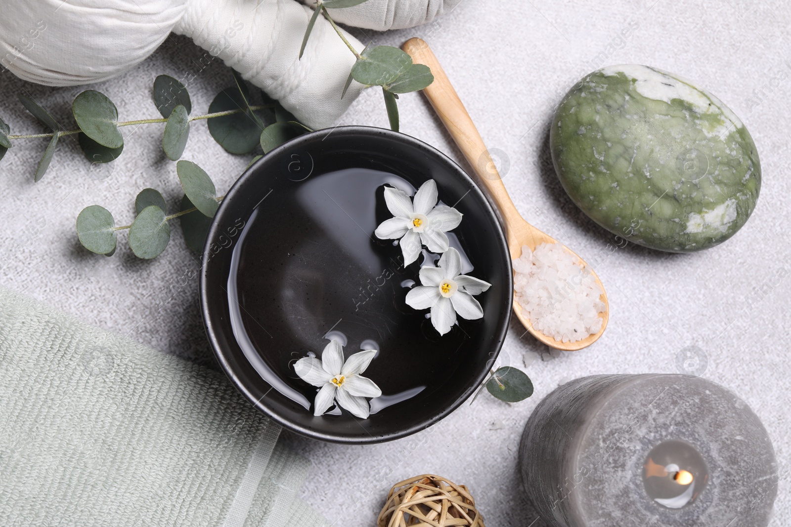 Photo of Flat lay composition with herbal massage bags, spa products and flowers on light grey table