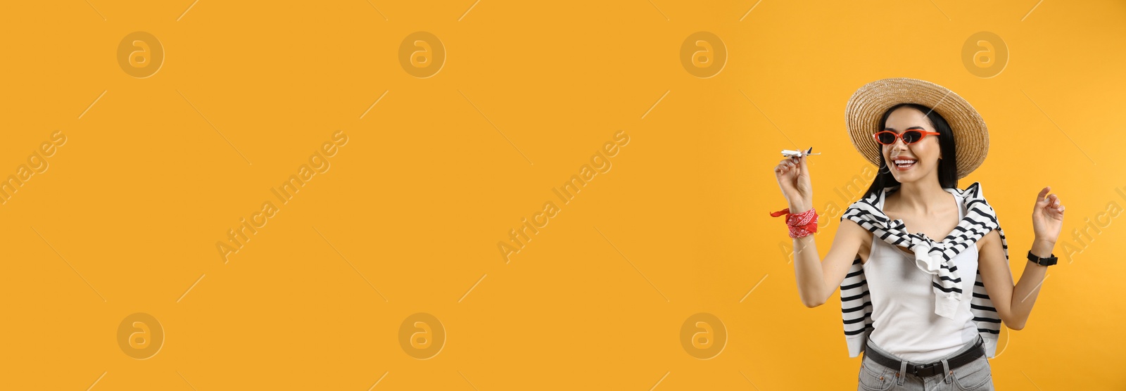 Photo of Happy female tourist with toy plane on yellow background. Space for text