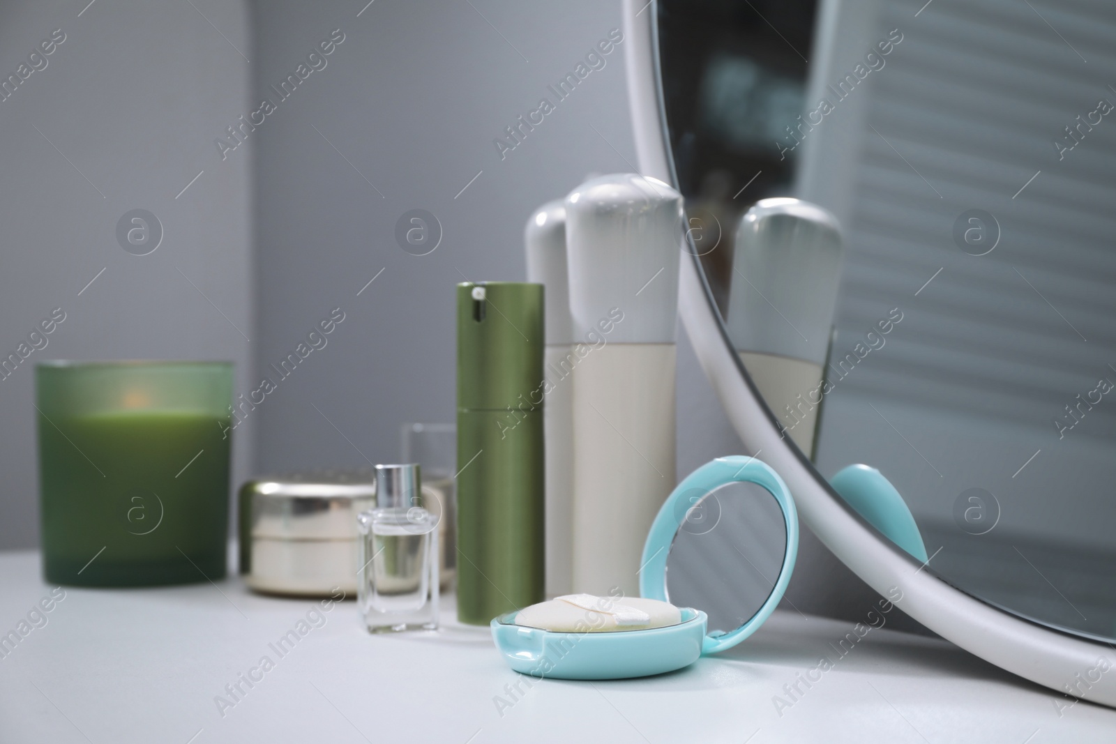 Photo of Stylish round mirror on dressing table with cosmetic products