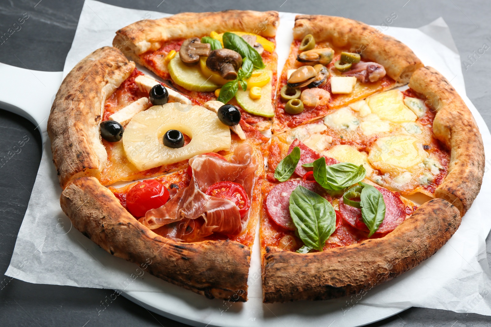 Photo of Slices of different pizzas on grey table, closeup