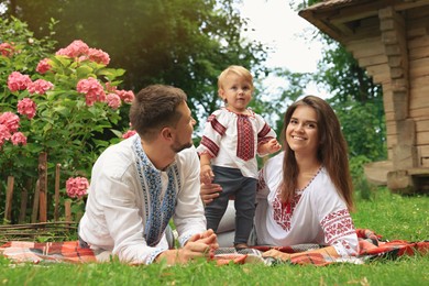 Happy family in Ukrainian national clothes on green grass outdoors