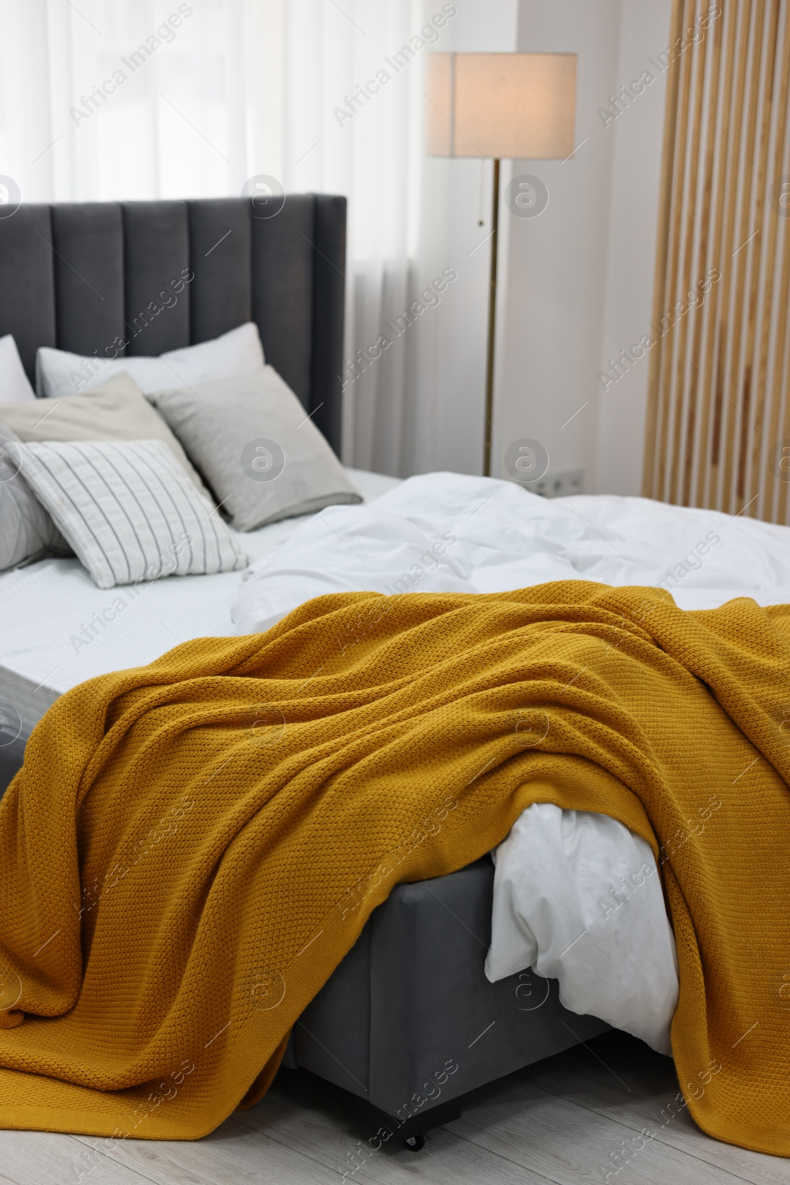 Photo of Bright plaid on bed in stylish bedroom