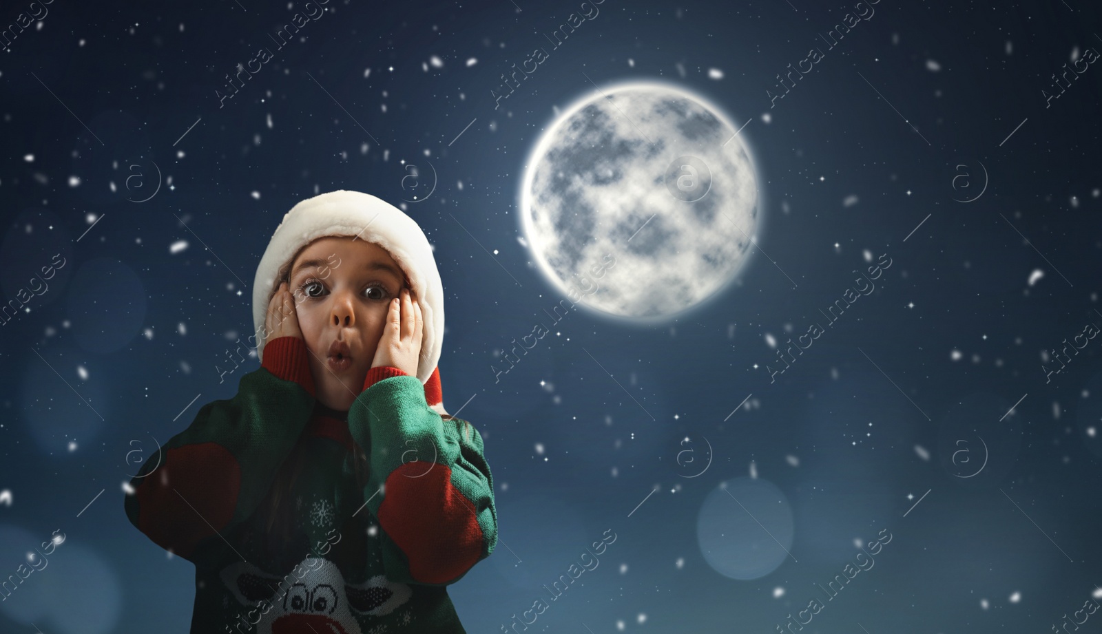 Image of Surprised little girl in Santa hat on full moon night. Christmas holiday 