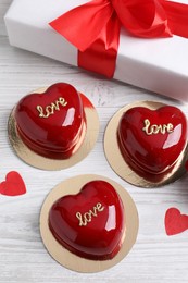 Photo of St. Valentine's Day. Delicious heart shaped cakes and gift on white wooden table