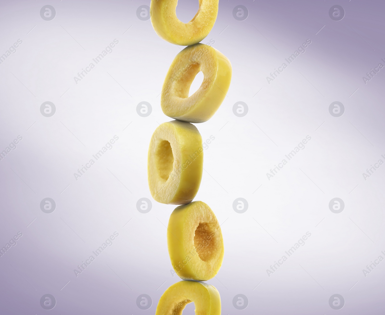 Image of Stacked slices of green olive on pastel purple gradient background