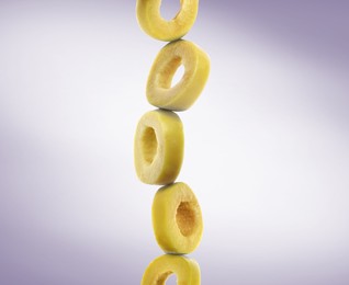 Image of Stacked slices of green olive on pastel purple gradient background