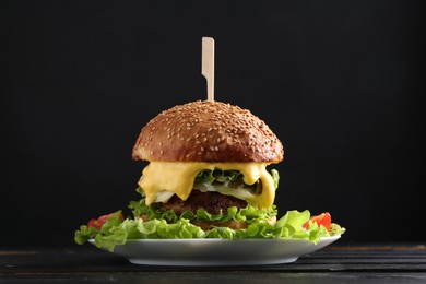 Vegetarian burger with delicious patty and cheese on black wooden table