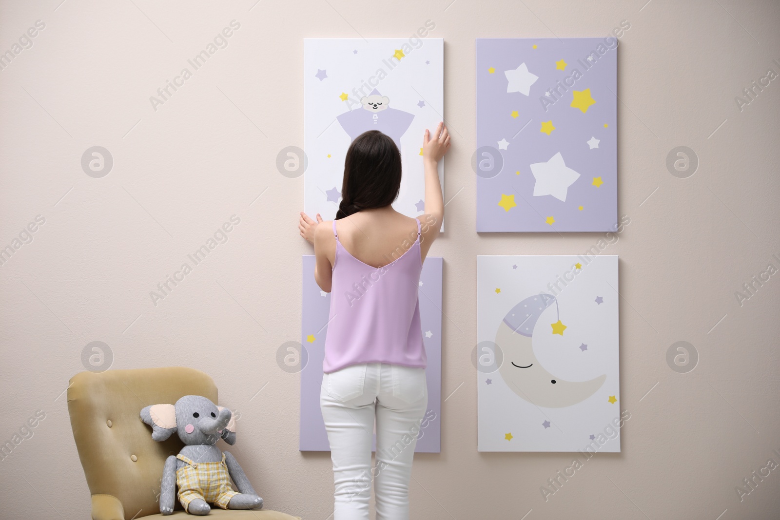 Photo of Decorator hanging picture on pink wall. Children's room interior design