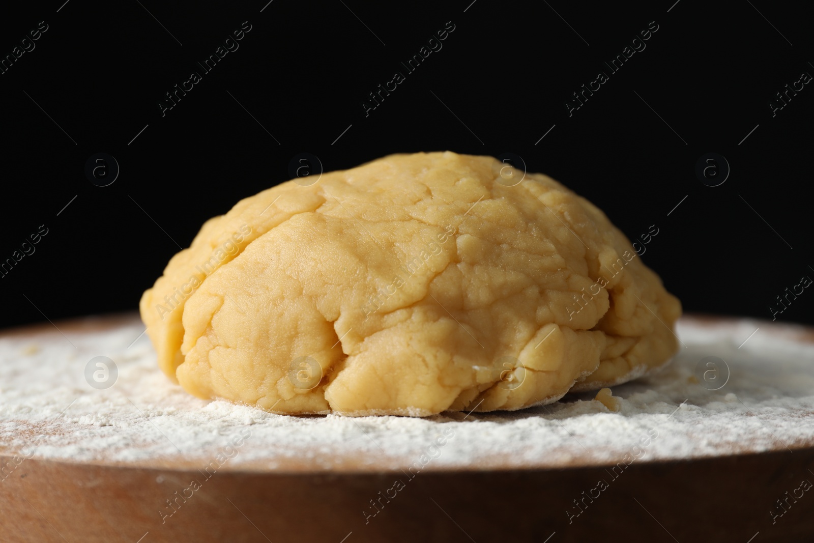 Photo of Making shortcrust pastry. Raw dough and flour on board, closeup