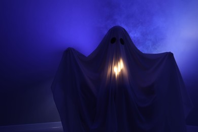 Photo of Creepy ghost. Woman covered with sheet in blue light