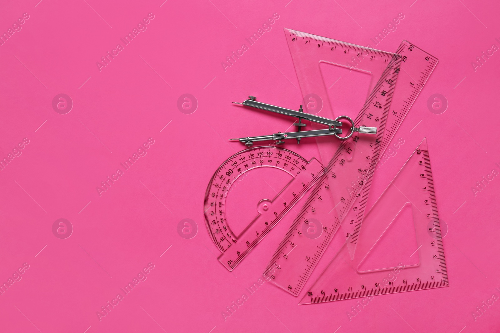 Photo of Flat lay composition with different rulers and compass on pink background. Space for text