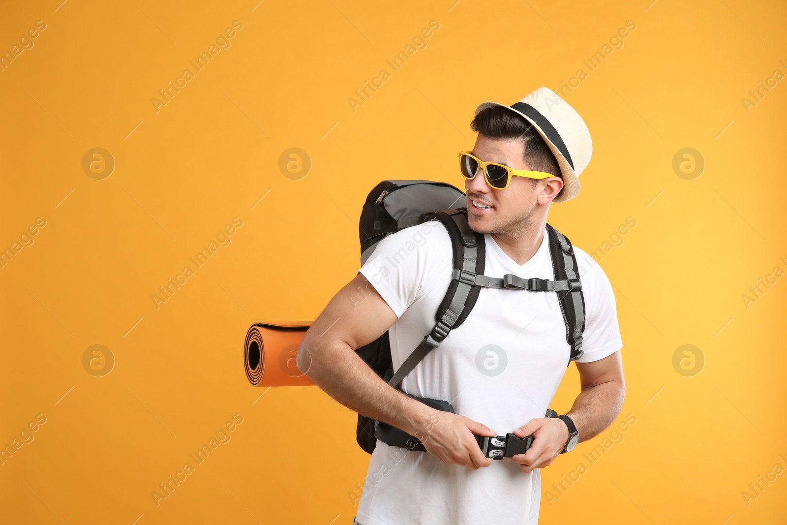 Photo of Male tourist with travel backpack on yellow background, space for text