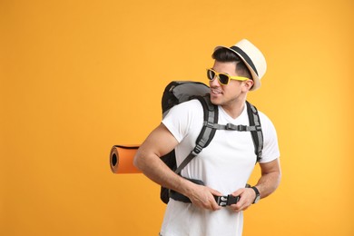 Male tourist with travel backpack on yellow background, space for text