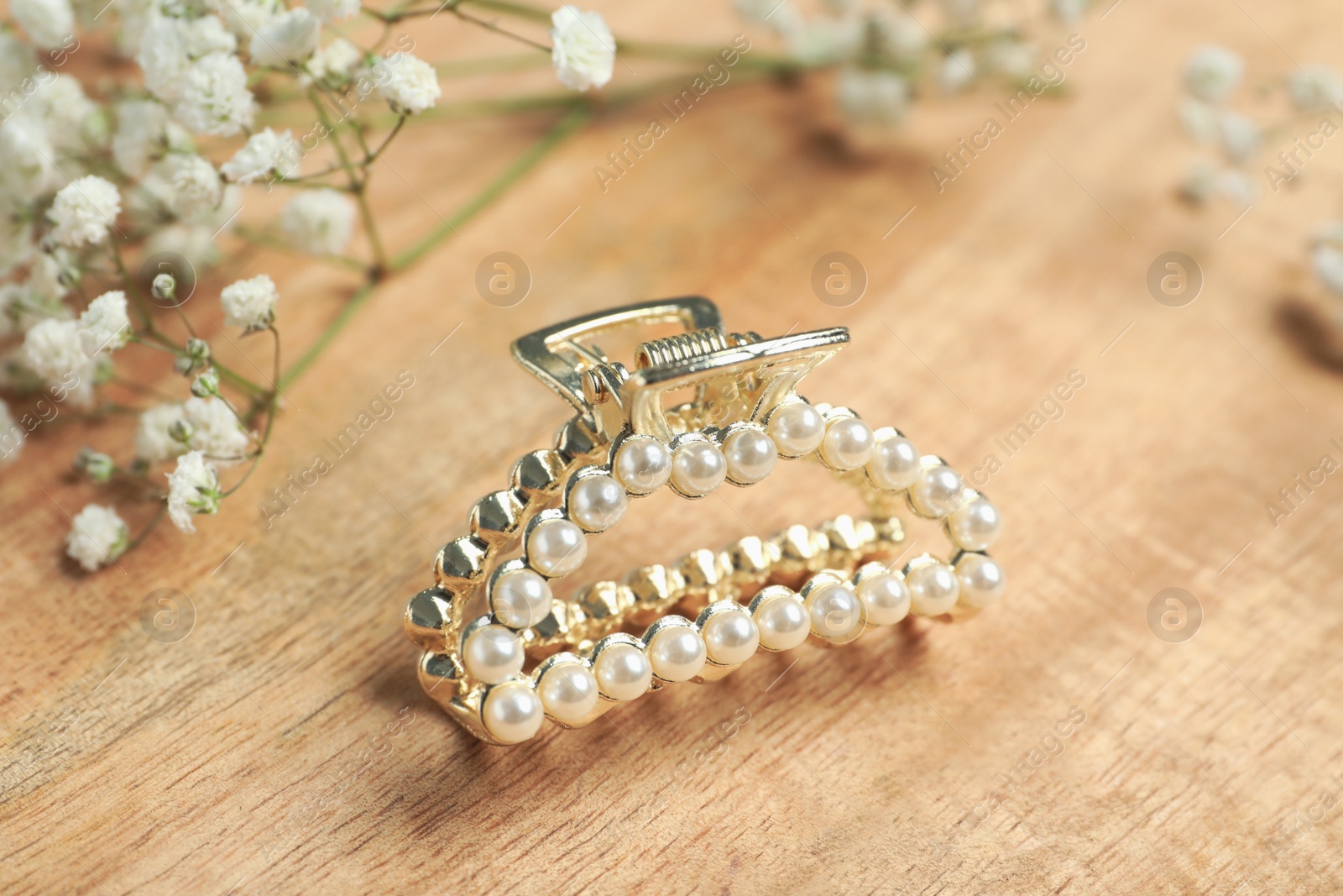 Photo of Stylish hair claw and flowers on wooden table