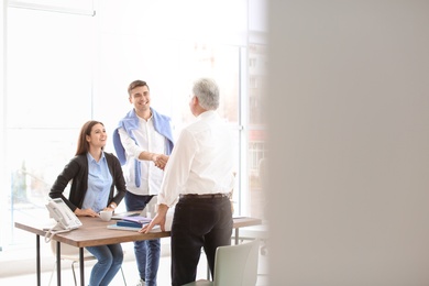 Human resources manager shaking hands with applicant during job interview in office