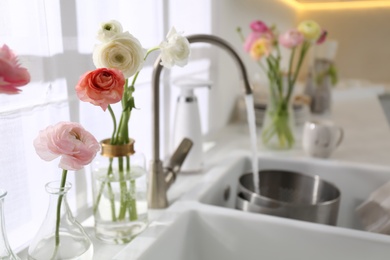 Photo of Light kitchen decorated with beautiful fresh ranunculus flowers